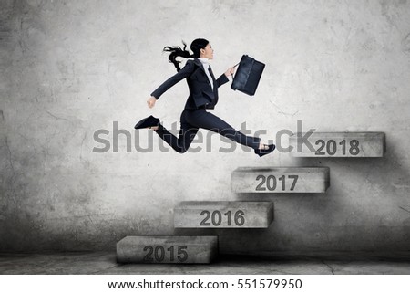 Picture of female entrepreneur running on the stairs with number 2017 toward 2018 while carrying a briefcase 