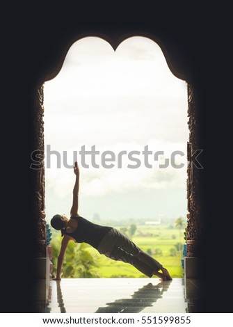 Silhouette young woman practicing yoga on the temple at sunset, vintage style color effect