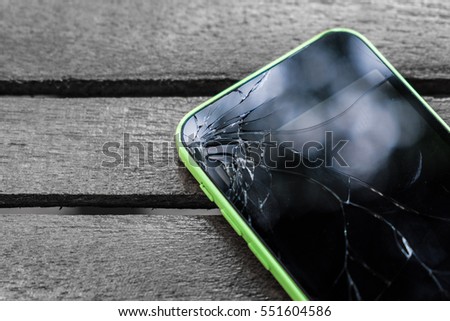 Broken screen glass of mobile smartphone on the wood table