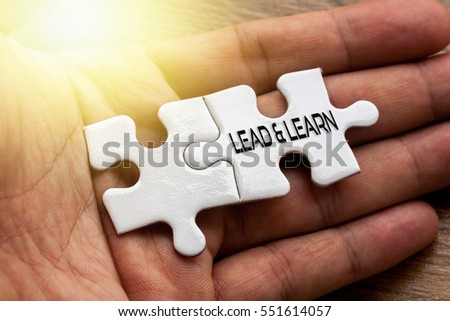 LEAD & LEARN written on White color of jigsaw puzzle with hand,conceptual