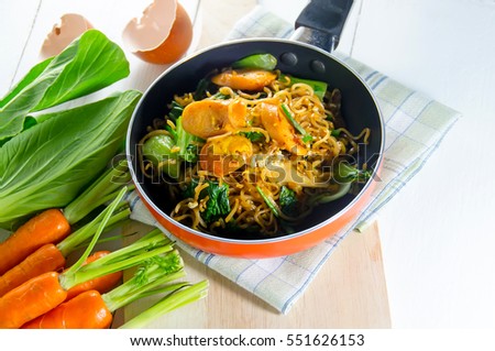 Fried noodle in pan on white table with fresh vegetables from the fram.