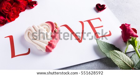 Word love with homemade meringue in heart shape with red roses. Valentines day concept, copy space