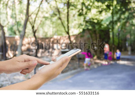Man use mobile phone, blur image of mother and children in the zoo as background.