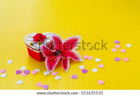 Valentine"s Day Concept : A Gift box with white lid have a red flower on top decorated by  spring of heart shape with red flower on the side on yellow background.
