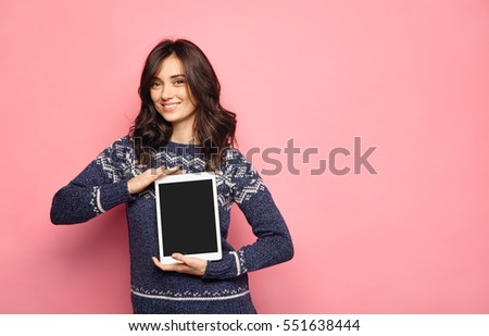 Pretty smiling woman showing black screen of digital tablet