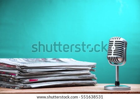 Retro microphone with newspaper on wooden table - announcement concept Royalty-Free Stock Photo #551638531