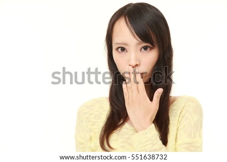 portrait of young Japanese woman making the speak no evil gesture