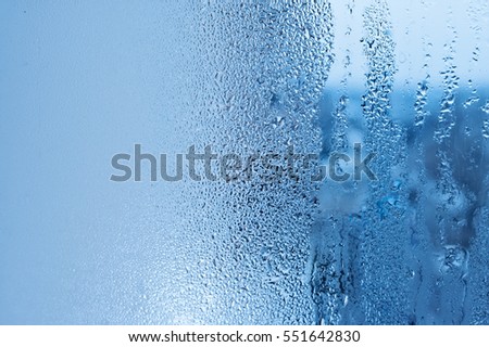 Window glass with condensation, strong, high humidity in the room, large water droplets flow down the window, cold tone, natural water drops on window