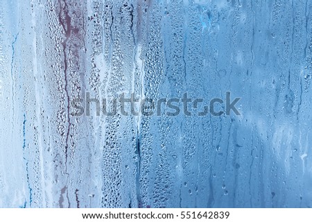 Window glass with condensation, high humidity in the room, large water droplets, cold tone Royalty-Free Stock Photo #551642839