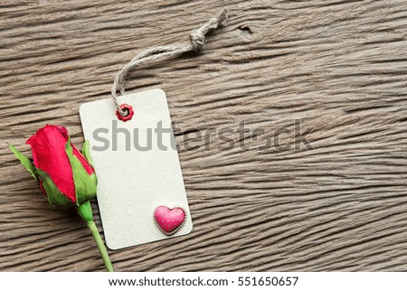 Valentines day background with heart, rose and tag on wood background.