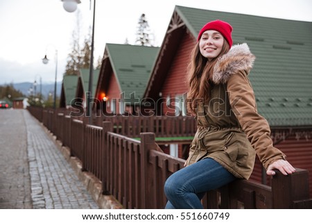 Picture of young pretty woman sitting outdoors and looking at camera.