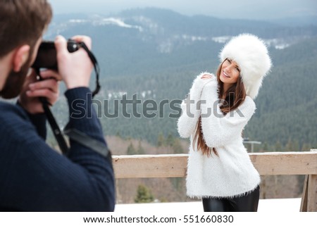 Picture of young attractive man photographing the cheerful woman over mountains.