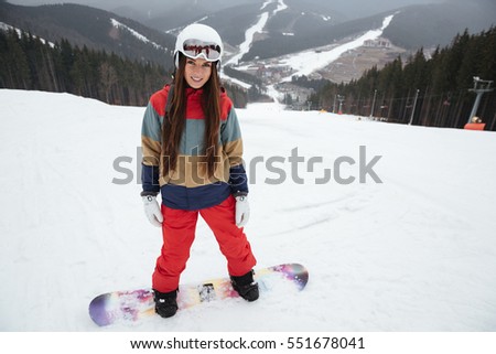 Photo of young pretty lady snowboarder on the slopes frosty winter day. Look at camera.