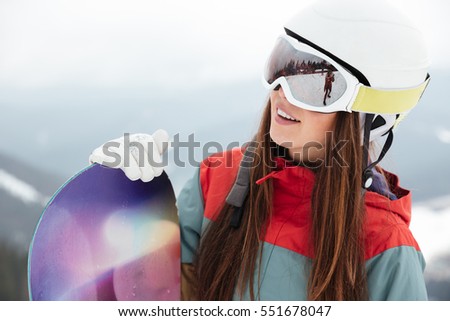 Photo of pretty woman snowboarder on the slopes frosty winter day. Look aside.