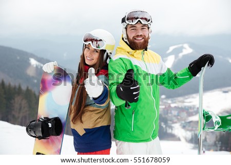 Photo of cheerful loving couple snowboarders on the slopes frosty winter day making thumbs up gesture. Look at camera.