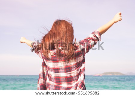 Woman relaxing at beach enjoying summer freedom with open arms and hair in the wind by the water seaside. Asian girl on summer travel holidays vacation outside. Vintage effect style pictures.