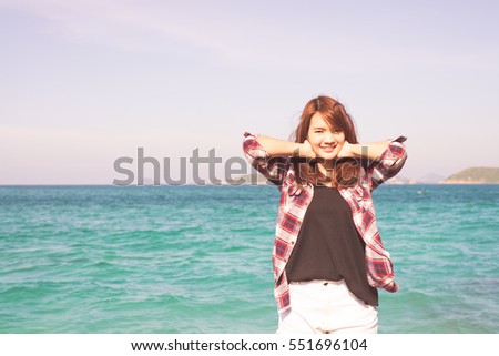 Woman relaxing at beach enjoying summer freedom with open arms and hair in the wind by the water seaside. Asian girl on summer travel holidays vacation outside. Vintage effect style pictures.