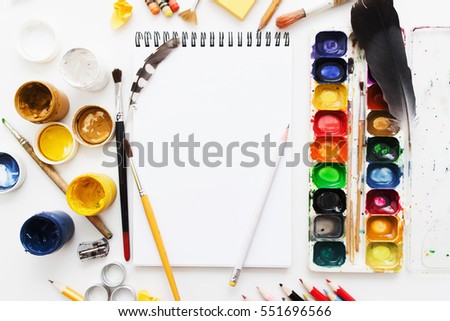 Creative artist workplace flat lay, mockup. top view on table with blank sketchbook, pencils, paintbrushes and dye palettes. Art, workshop, painting, drawing, craft, creativity concept