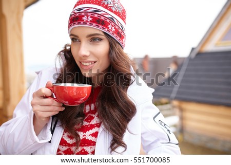 Beautiful woman with mug of coffee in ski resort, winter season, smiling