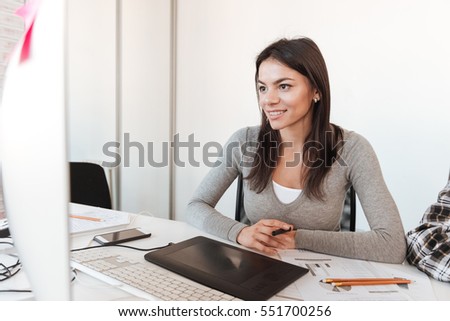 Photo of young happy businesswoman using computer in office. Look at computer.