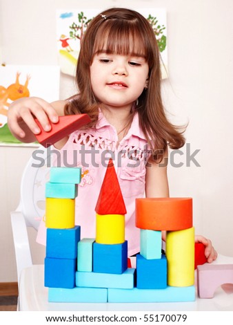 Little girl with wood block in play room.