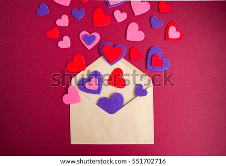 Colored hearts pours out of the envelope. Burgundy background.