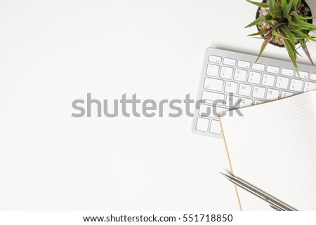 White office desk table with notebook, pen and computer keyboard.