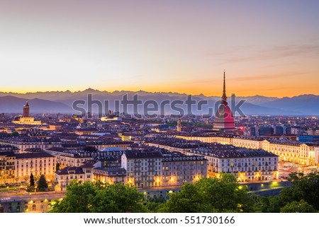 Italia: Torino skyline (Turin, Italy), cityscape at sunset, the Mole Antonelliana and the town illuminated at twilight. Scenic colorful sky over the snowcapped Alps in the background. Royalty-Free Stock Photo #551730166