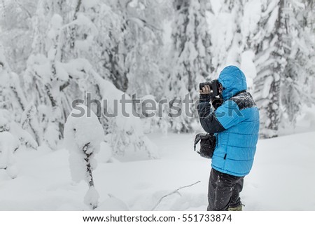 Photographer in blue jacket in winter woods