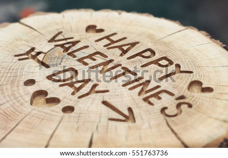 Happy Valentine's Day. Woodcarving handwork. Vintage on an old tree stump with cracks. Greeting card with hearts, arrows and message.