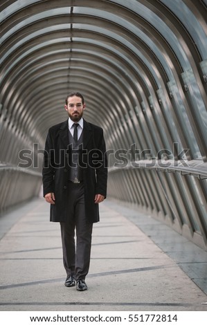 Young businessman walking on futuristic pedestrian bridge at the Defense District. Paris, France. 