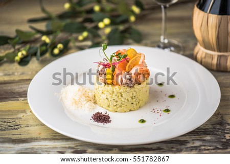 Risotto with seafood. Rice in white plate close-up on a wooden table. Royalty-Free Stock Photo #551782867