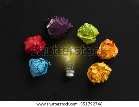 Idea concept with bulb and different colors paper wads  on  black background