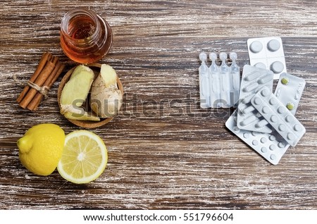 Ginger, lemon, honey and  different drugs on wooden background.Alternative remedies and traditional pills to treat colds and flu. Natural medicine vs conventional medicine concept.  Royalty-Free Stock Photo #551796604