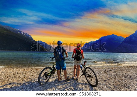 Mountain biking, couple with bikes at sunset on Lake Garda, Riva del Garda, Italy