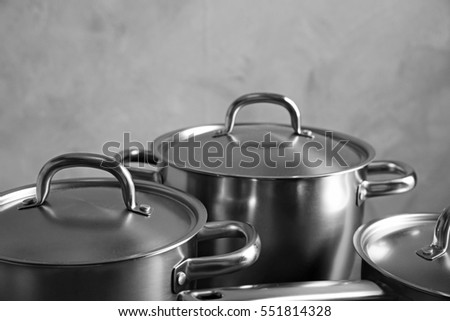 Kitchenware concept. Stainless saucepans on grey textured background