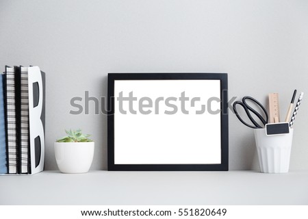 Modern home decor mock up. Creative desk with blank picture frame or poster, desk objects, office supplies, books and plant on a gray background. 