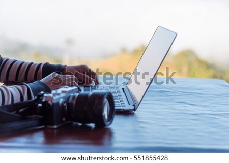 Hands of woman using laptop computer and camara  on  working in a coffee shop
