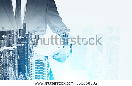 Close up of a businessman holding a hardhat standing against a city panorama. Film effect. Mock up. Toned image. Double exposure