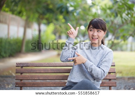 Happy woman at park pointing to copy space 