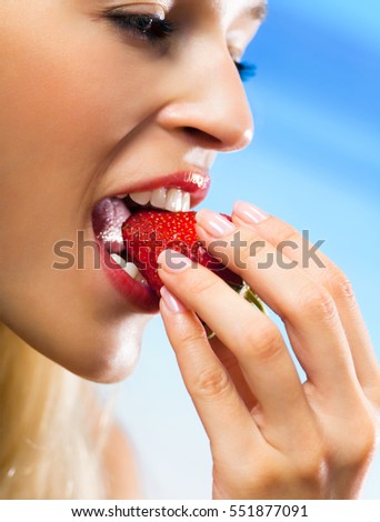 beautiful woman eating strawberry on beach