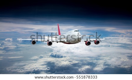 White passenger jet plane in the blue sky.  Aircraft flying high through the clouds. Airplane front view. Royalty-Free Stock Photo #551878333