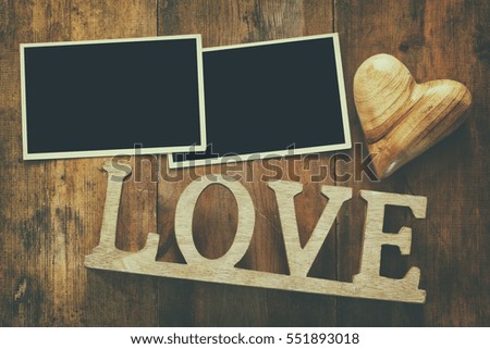 Top view of empty photo frames next word LOVE from wooden letters and hearts over the table. Ready to put photographs. Flat lay. Retro filter