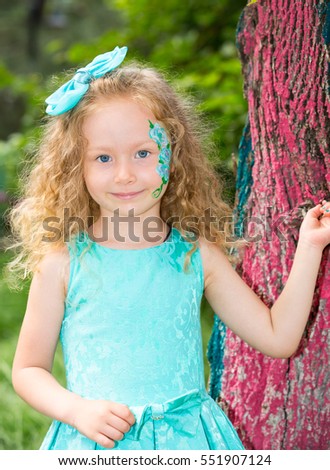Beautiful happy girl kid with aqua make-up on birthday in park. Celebration concept and childhood, love