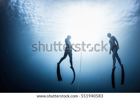 Two free divers, man and woman, ascending from the depth Royalty-Free Stock Photo #551940583