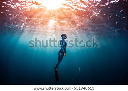 Woman free diver ascending from the depth in a tropical clear sea Royalty-Free Stock Photo #551940613