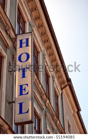 An unlit neon hotel sign situated next to the room windows