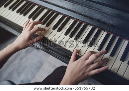 The girl plays piano, close up , white and black keyboard