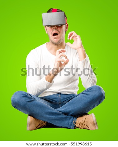Seated young man using a virtual reality glasses