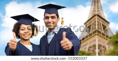 education, graduation, gesture and people concept - happy international students in mortar boards and bachelor gowns outdoors showing thumbs up over eiffel tower background